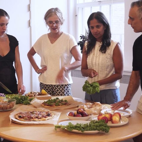 Medarbejdere står sammen om et bord i køkkenet og laver mad